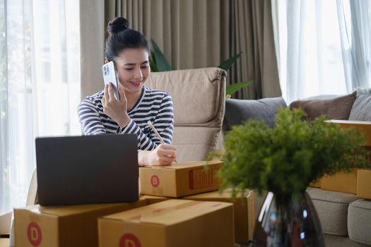 Asian small business owner checking order by smartphone at home office. Business retail market and online sell marketing delivery, SME e-commerce concept