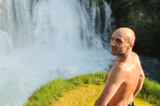 standing man with wide opened arms with waterfalls in background and representing freshness healthy lifestyle and success concept