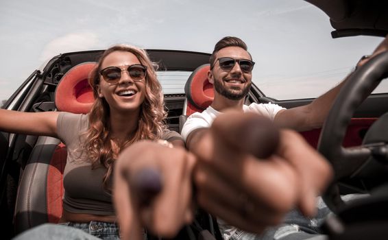 close up.young couple sitting in a convertible and pointing at you.the concept of choice