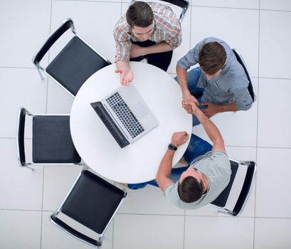 handshake of the colleagues sitting around the table.the concept of cooperation