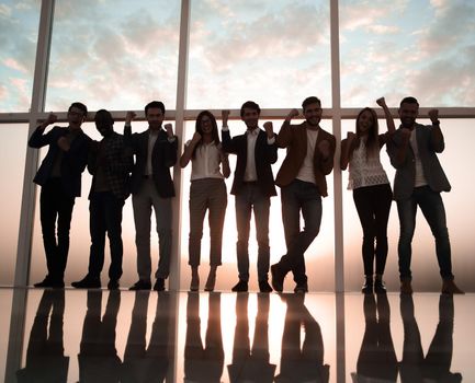 group of young professionals standing in an office with a large window. the concept of employment