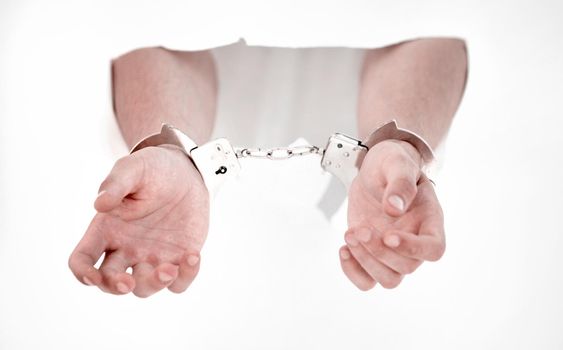 Handcuffs on the hands of a man breaking a paper wall.photo with copy space