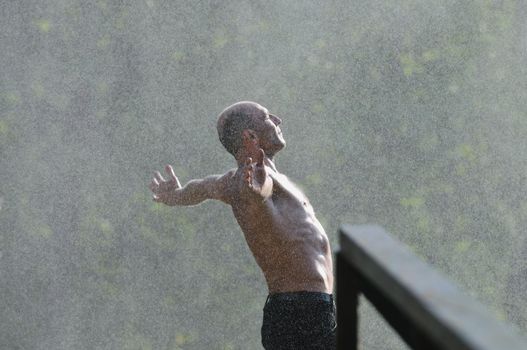 standing man with wide opened arms with waterfalls in background and representing freshness healthy lifestyle and success concept