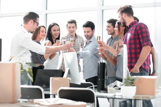 business team raising wine glasses while standing in the office.the concept of a startup