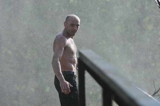 standing man with wide opened arms with waterfalls in background and representing freshness healthy lifestyle and success concept