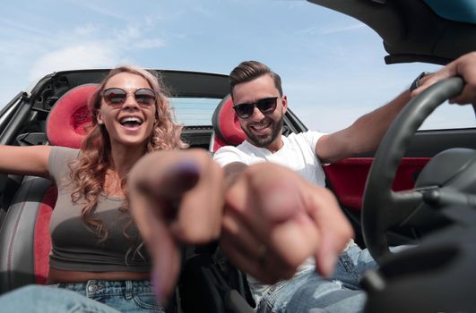 close up.happy couple sitting in the car and pointing at you.the concept of choice