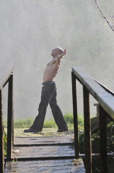 standing man with wide opened arms with waterfalls in background and representing freshness healthy lifestyle and success concept