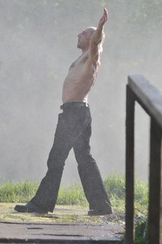 standing man with wide opened arms with waterfalls in background and representing freshness healthy lifestyle and success concept