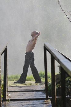 standing man with wide opened arms with waterfalls in background and representing freshness healthy lifestyle and success concept