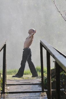 standing man with wide opened arms with waterfalls in background and representing freshness healthy lifestyle and success concept