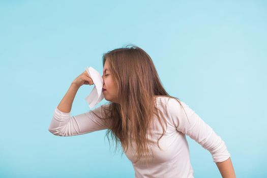 Young woman with handkerchief. Sick girl isolated has runny nose on blue background.