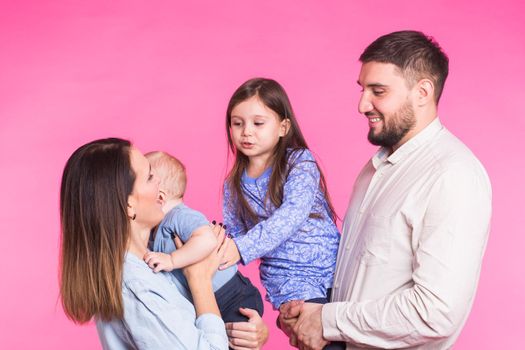 Happy family portrait smiling on pink background.