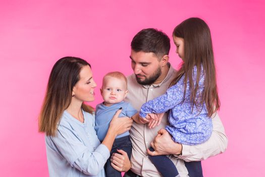 Portrait of Young Happy Mixed Race Family over pink background.