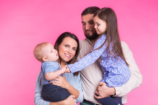 Portrait of Young Happy Mixed Race Family over pink background.