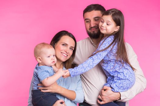 Happy family portrait smiling on pink background.