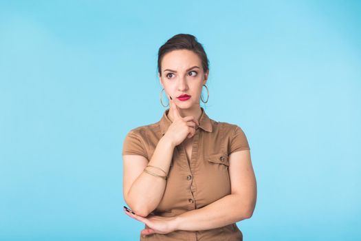 Concerned scared woman on blue background in studio