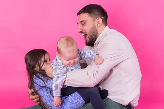 Father with children having fun on pink background.