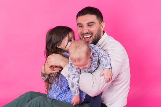 Father with children having fun on pink background.