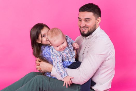 Father with children having fun on pink background.