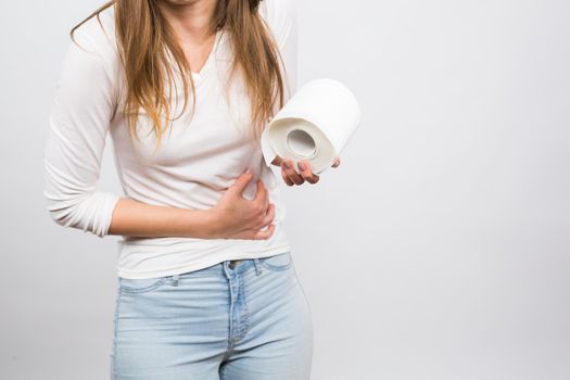 Woman with stomach pain and toilet paper roll on white background.