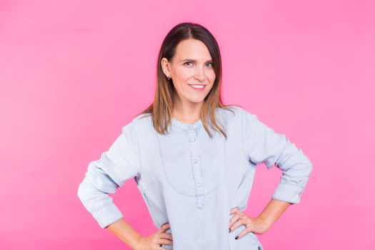 Smiling Woman in shirt posing in studio on pink background.