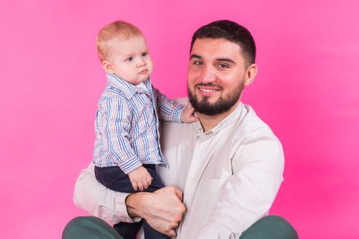 happy father with a baby son isolated on a pink background.
