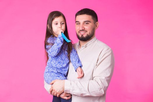 Happy father with his baby daughter on pink background.