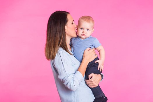 happy young mother with a baby child on pink background.