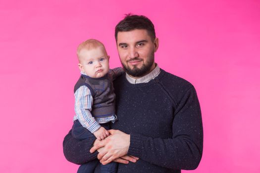 happy father with a baby son isolated on a pink background.
