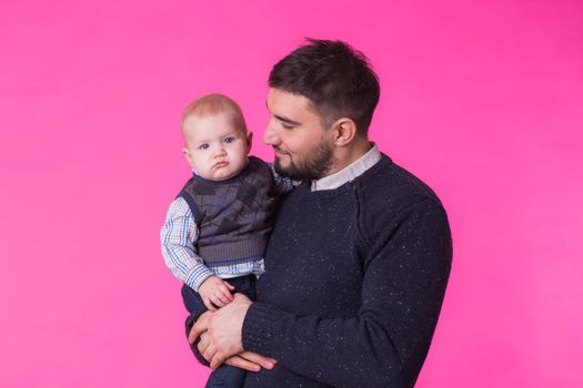 happy father with a baby son isolated on a pink background.