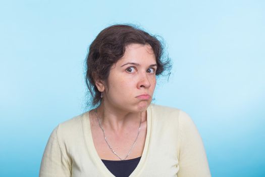 portrait of young angry woman on blue background.