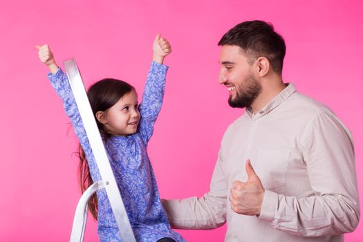 Father with his baby daughter shows thumb up.