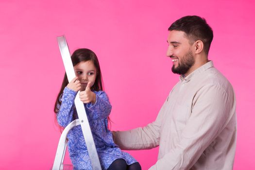 Father with his baby daughter smiling over pink background