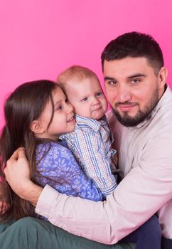 Father with children having fun on pink background.