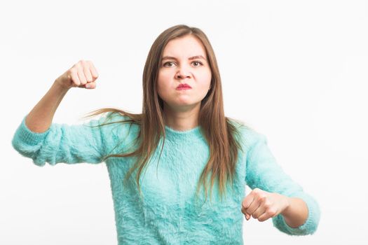 furious young brunette woman shows fist. The girl is very angry and ready to use his fists. Negative aggressive emotions on her face