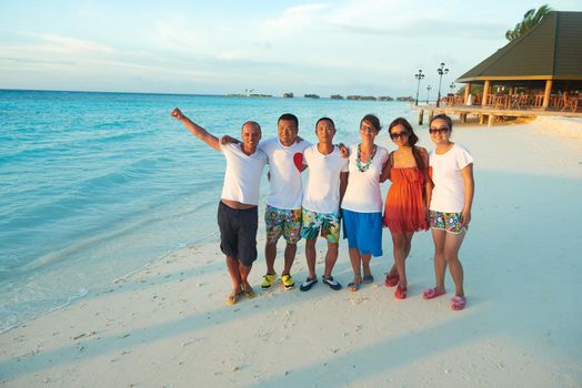 group of friends on beautiful beach at sunset going back to home