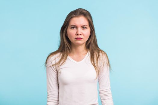 Portrait of sad woman standing on blue background.