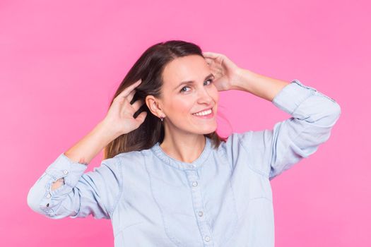 Smiling Woman in shirt posing in studio on pink background.