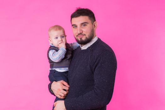 Happy father with his baby son on pink background.