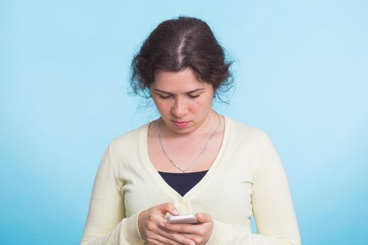 Girl texting on the smart phone over blue background.