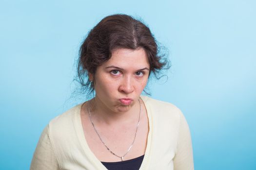 portrait of young angry woman on blue background.