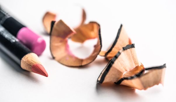 Sharp red lip pencils lying next to shavings