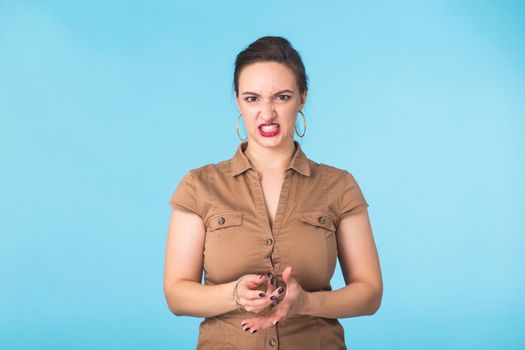 Angry aggressive woman with ferocious expression on blue background.