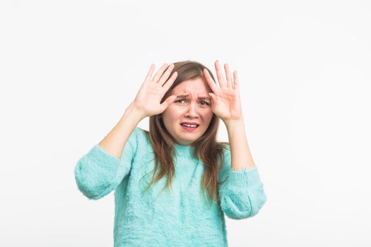 Scared stressful woman with bugged eyes looking terrified into camera. Fearful beautiful young female in casual clothes having bad reaction on horror news .