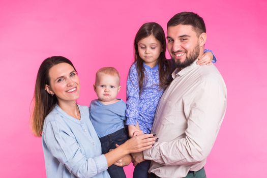 Happy family portrait smiling on pink background.
