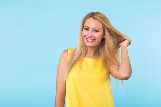 beauty fashion summer portrait of blonde woman with red lips and yellow dress on blue background with copy space.