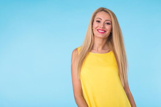 beauty fashion summer portrait of blonde woman with red lips and yellow dress on blue background with copy space.