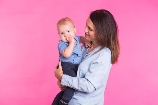 happy young mother with a baby child on pink background.