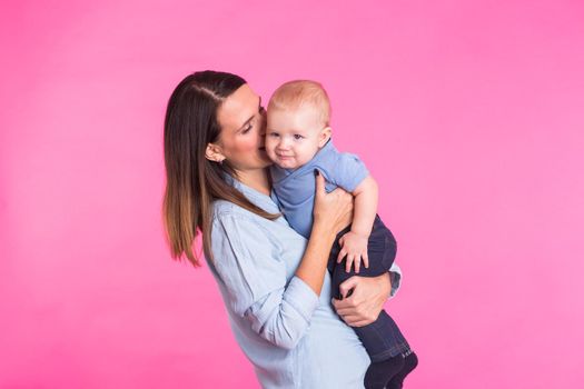 happy young mother with a baby child on pink background.