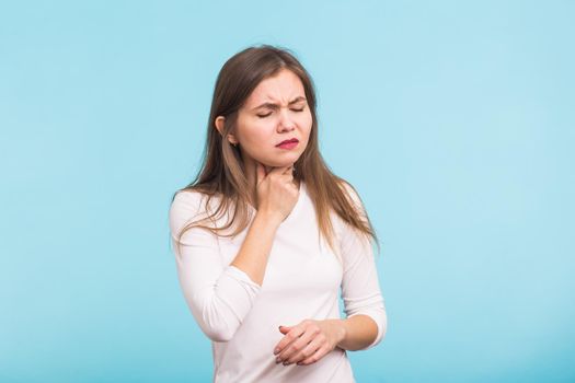 Sore throat. Woman touching the neck on blue background.